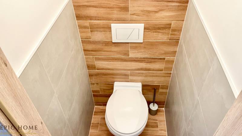 Toilette mit Holzverkleidung in einer Einzimmerwohnung, die Farben und Texturen harmonisch kombiniert.