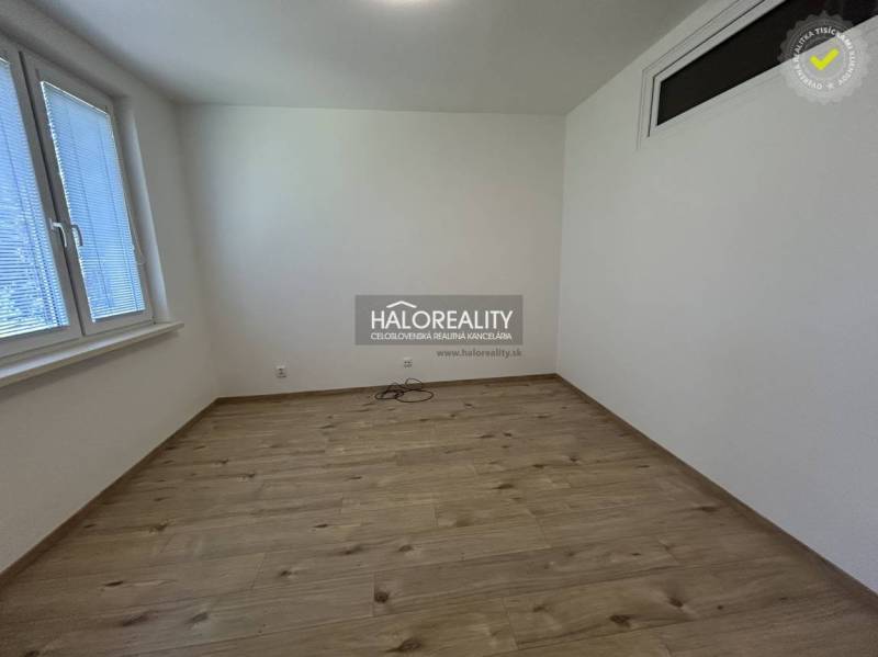Ein leerer Raum mit Holzboden und zwei Fenstern in einer 3-Zimmer-Wohnung.