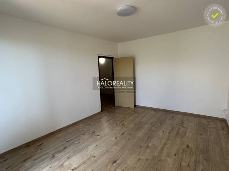 Ein leerer Raum mit Holzboden in einer 3-Zimmer-Wohnung, weiße Wände, offene Türen.