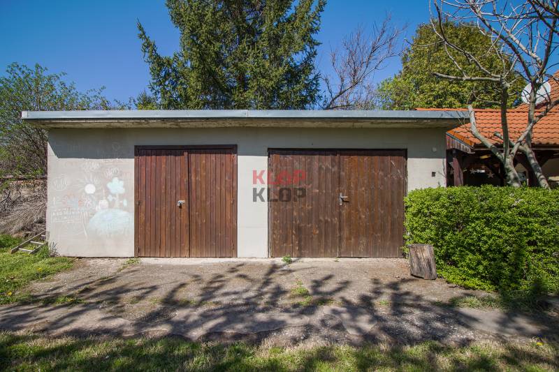 Doppelgarage bei einem Einfamilienhaus in Veľká Paka mit Holztüren und Gartenumgebung.