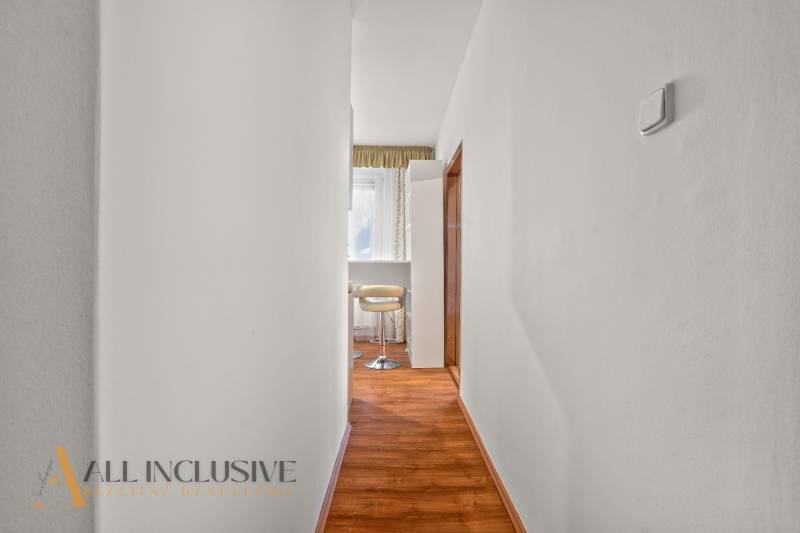 Ein enger Flur in einer 2-Zimmer-Wohnung mit Holzboden und hellen Möbeln.