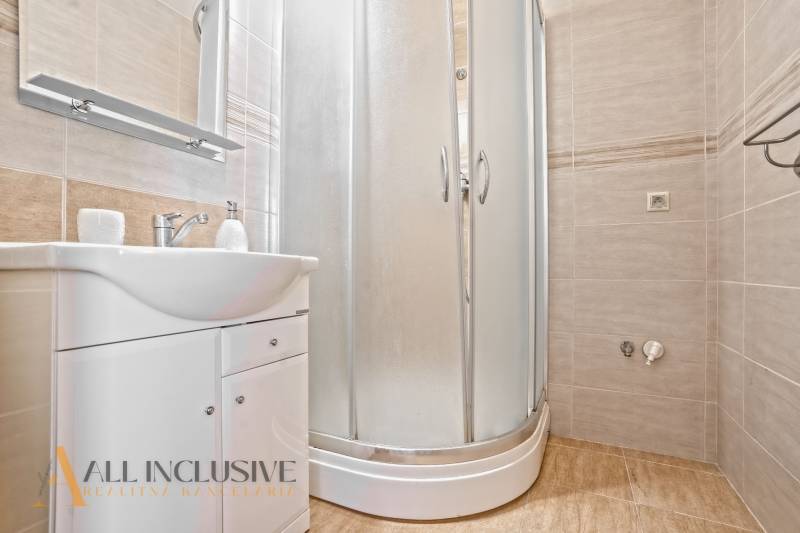 Badezimmer mit Waschbecken und Duschkabine in einer 2-Zimmer-Wohnung.