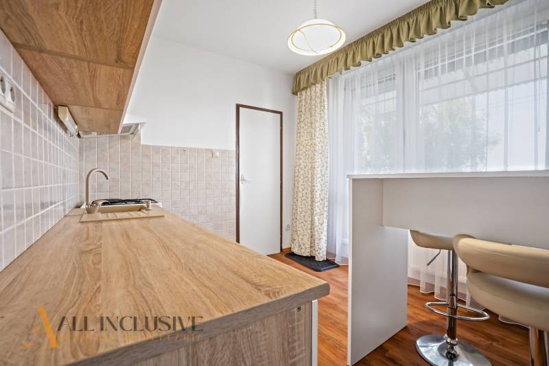 Küche in einer 2-Zimmer-Wohnung mit einer Arbeitsplatte aus Holz und hohen Stühlen.