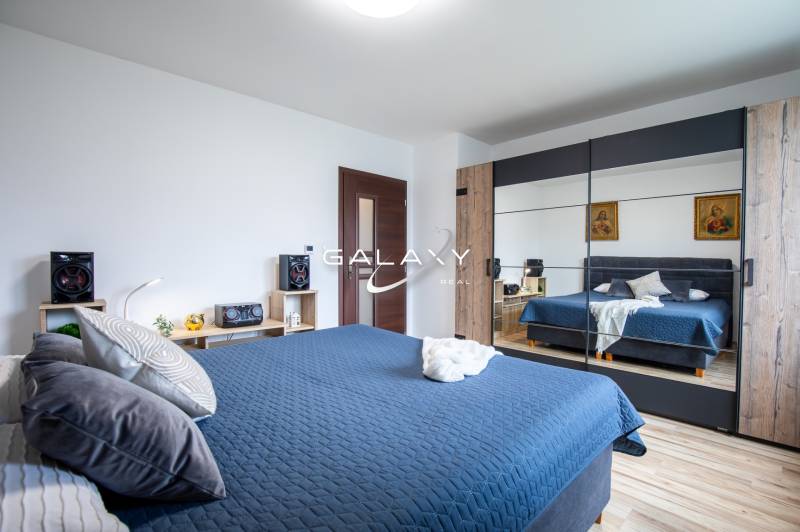 Schlafzimmer mit einem Spiegelschrank in einem Einfamilienhaus, blaue Bettwäsche und Holzdekorationen.