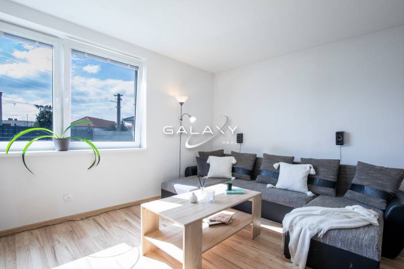 Helles Wohnzimmer in einem Einfamilienhaus mit einem bequemen Sofa, einem Tisch und einem großen Fenster.