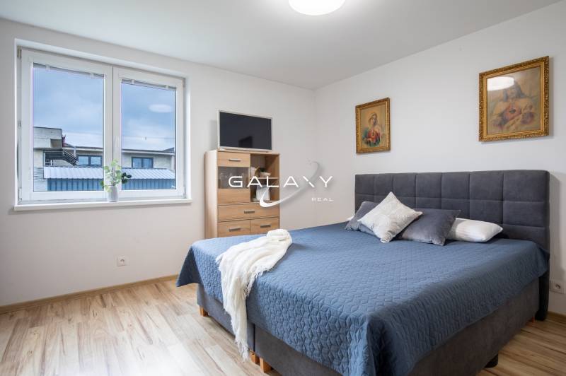 Schlafzimmer im Einfamilienhaus mit Ehebett, Bildern und Fenster.