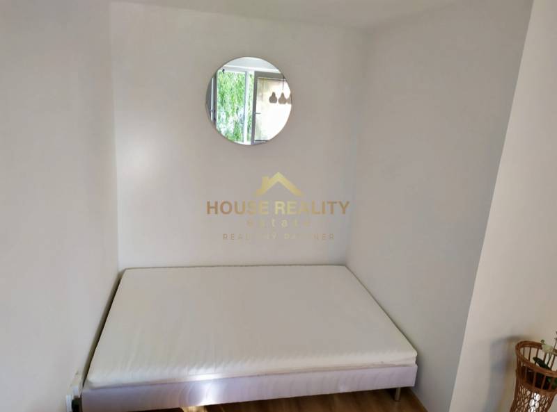 Ein Bett, ein rundes Spiegel und Holzboden in einer Einzimmerwohnung.