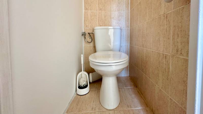 Toilette mit weißer Schüssel und Fliesen in einer 3-Zimmer-Wohnung.