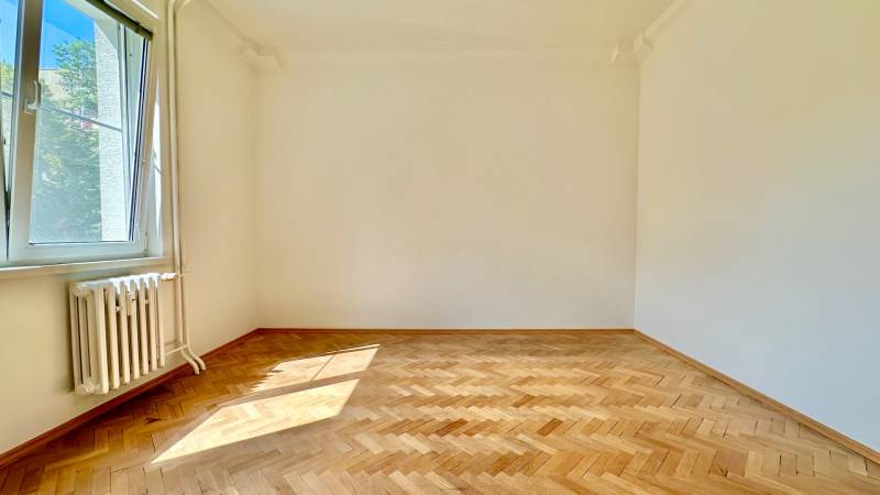 Ein leerer Raum mit Holzboden und einem großen Fenster in einer 3-Zimmer-Wohnung.