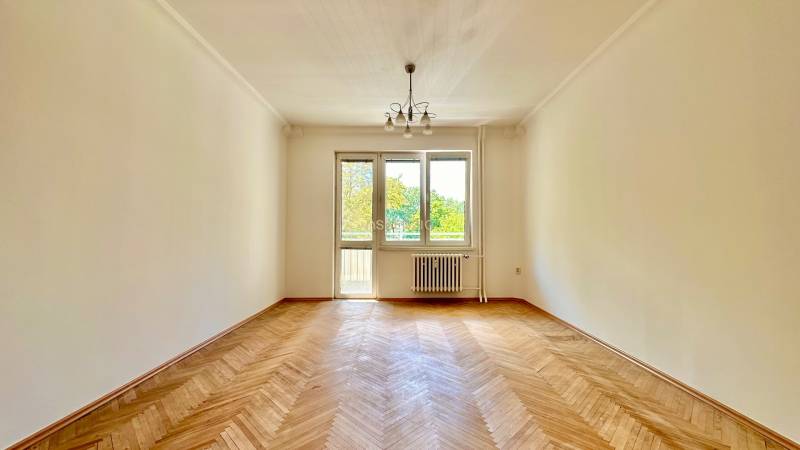 Ein geräumiges Zimmer in einer 3-Zimmer-Wohnung mit Parkettboden und großen Fenstern für viel Licht.