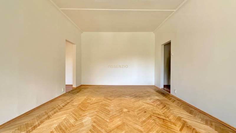 Ein geräumiges Zimmer in einer 3-Zimmer-Wohnung mit Holzboden und weißen Wänden.