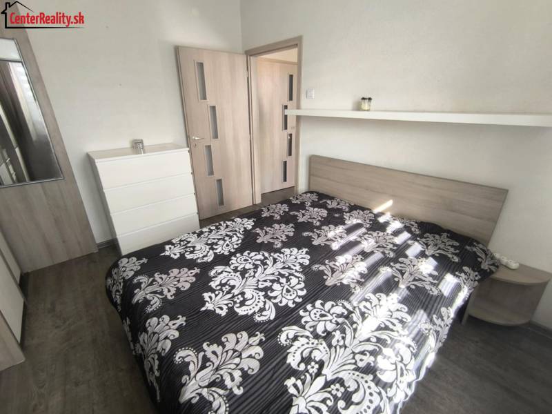 Schlafzimmer mit Bett, Kommode und Spiegel in einer 2-Zimmer-Wohnung.