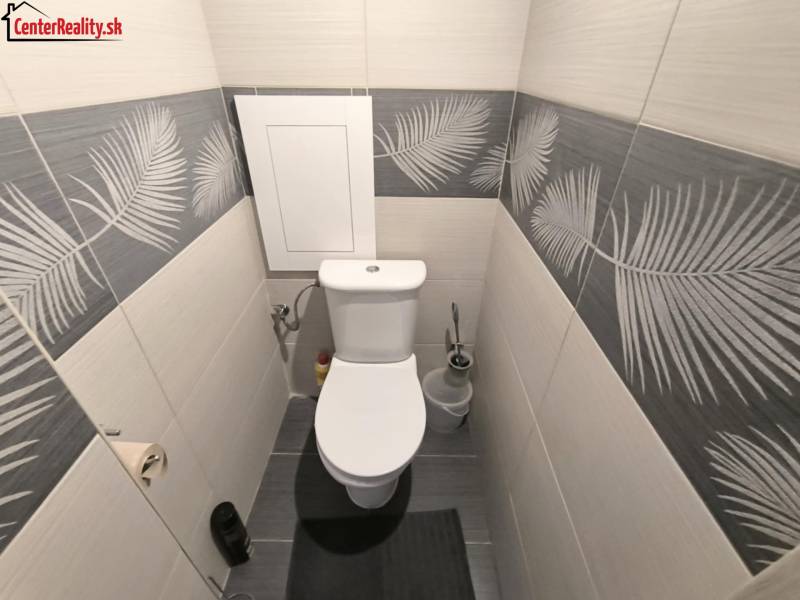 Toilette in einer 2-Zimmer-Wohnung, mit Fliesen im Blättermotiv.
