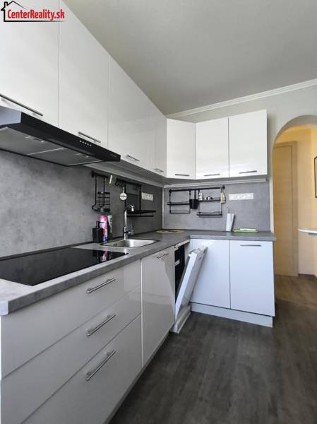 Eine Küche mit weißen Schränken, grauer Arbeitsplatte, eingebauten Geräten in einer 2-Zimmer-Wohnung.