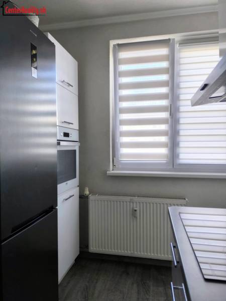 Küche in einer 2-Zimmer-Wohnung mit Kühlschrank, Ofen und Heizkörper, ideal für praktisches Wohnen.