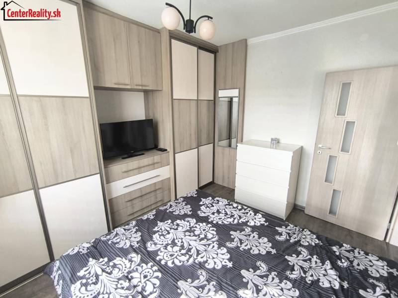 Schlafzimmer in einer 2-Zimmer-Wohnung mit Bett, Schrank, Fernseher und Einbauschrank.
