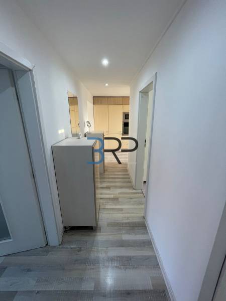 Der Flur in einer 2-Zimmer-Wohnung mit Holzboden und weißen Wänden.