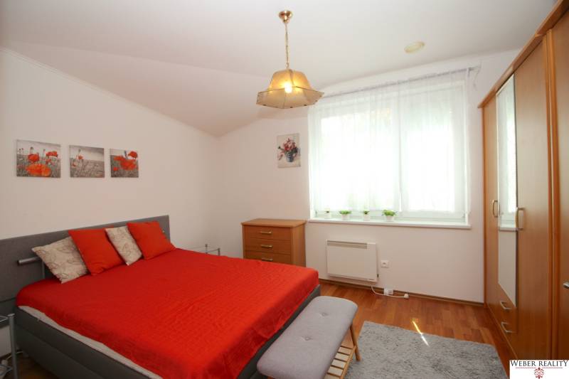 Schlafzimmer im Einfamilienhaus mit Ehebett, Holzmöbeln und roten Accessoires.