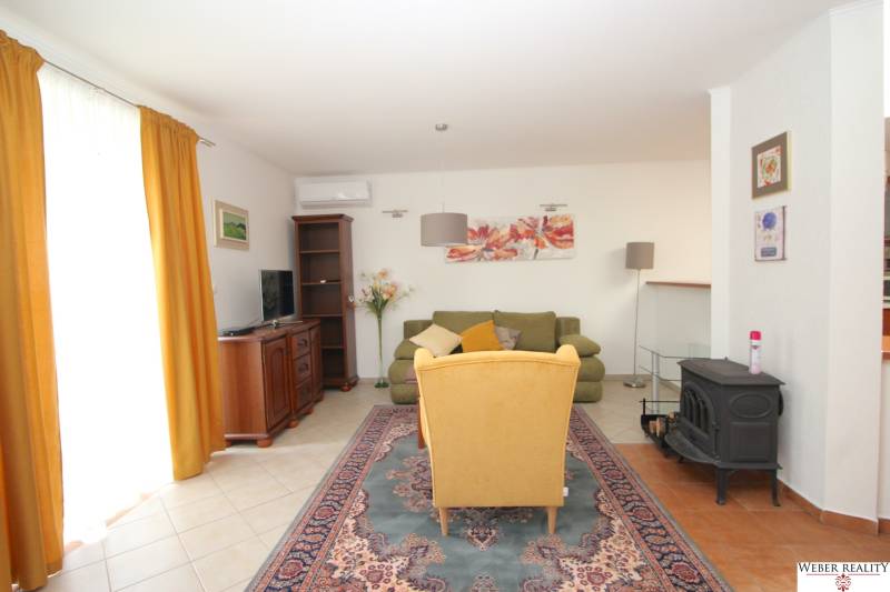Wohnzimmer mit Blumenbildern, gelbem Sessel und grünem Sofa in einem Einfamilienhaus.