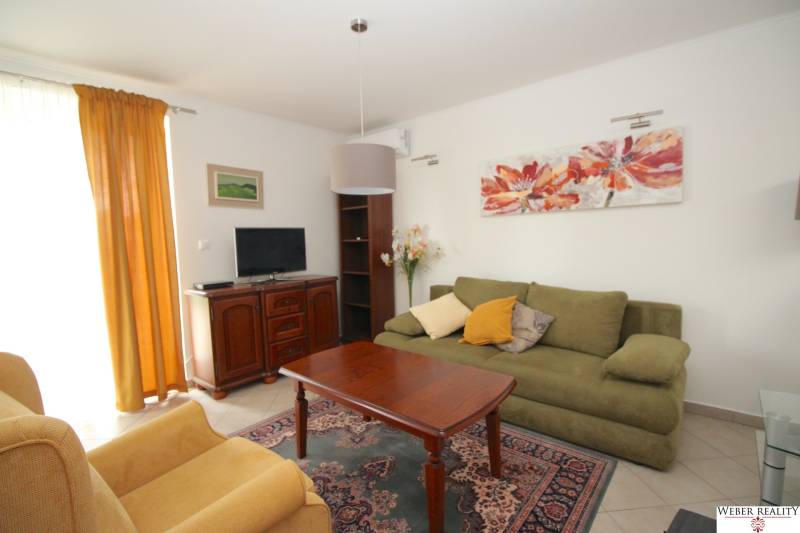 Wohnzimmer in einem Einfamilienhaus mit Sofa, Sessel, Tisch und Fernseher.