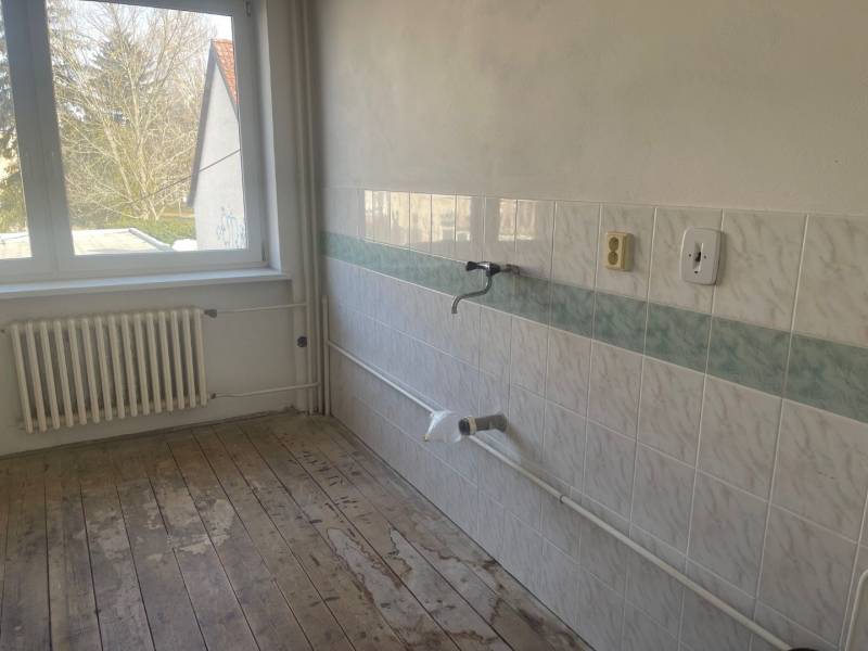 Eine leere Küche in einem Einfamilienhaus mit Fliesen und Holzboden.