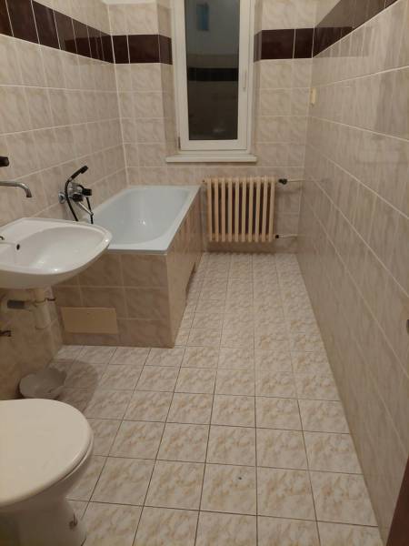 Badezimmer in einem Einfamilienhaus mit Badewanne, Waschbecken, WC und Heizkörper an der Wand.
