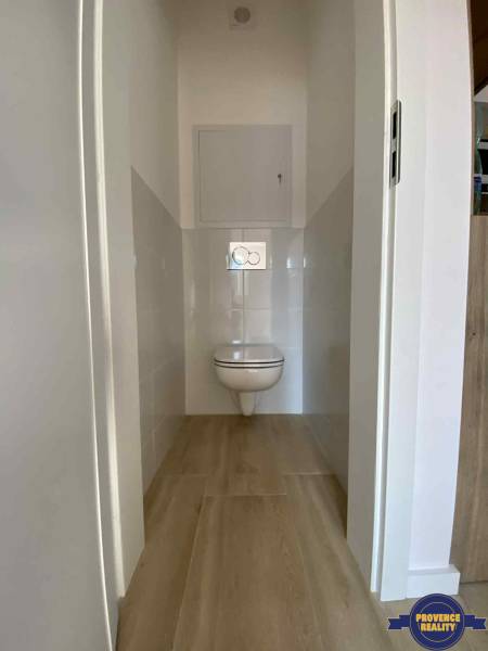 Toilette mit hängendem WC und Fliesen in einer 3-Zimmer-Wohnung, mit Holzboden.