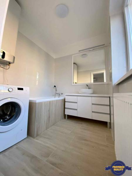 Badezimmer in einer 3-Zimmer-Wohnung mit Badewanne, Waschmaschine und Unterschrank.