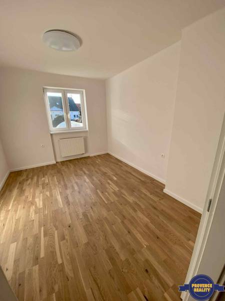 Ein Zimmer in einer 3-Zimmer-Wohnung mit Holzboden und weißen Wänden, ein Fenster mit Aussicht.