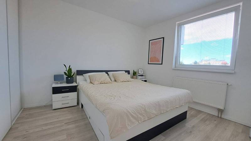 Helles Schlafzimmer mit Einrichtung und Bett in einer 2-Zimmer-Wohnung, minimalistisches Design.