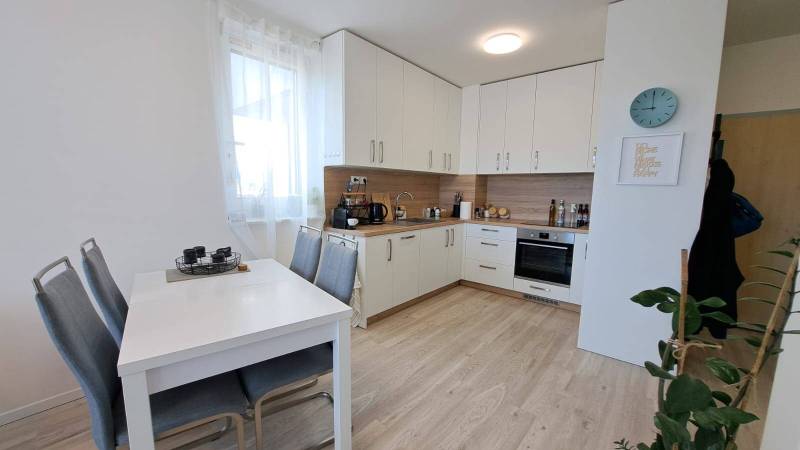 Küche in einer 2-Zimmer-Wohnung mit weißer Küchenzeile, Esstisch und Holzboden.