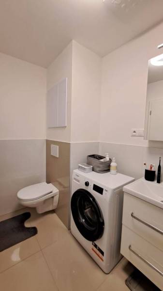 Badezimmer in einer 2-Zimmer-Wohnung mit Waschmaschine, Waschbecken und Toilette.