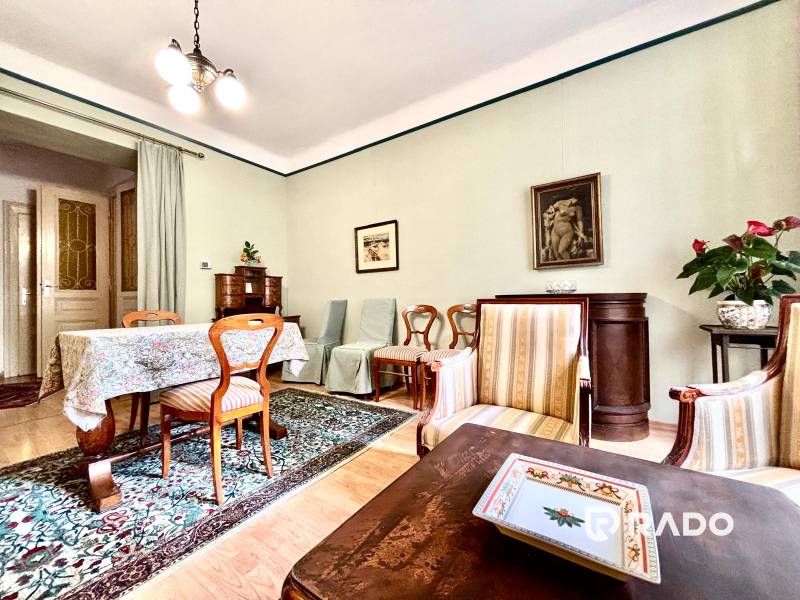 Wohnzimmer in einer 2-Zimmer-Wohnung mit Holzmöbeln und einem bunten Teppich.