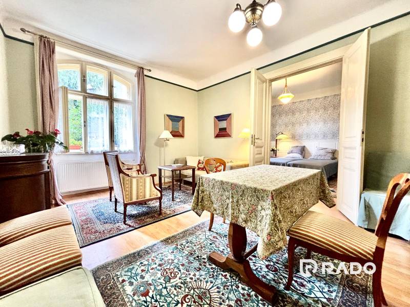 Traditionelles Interieur einer 2-Zimmer-Wohnung mit Teppich, Möbeln und Zimmerpflanzen.