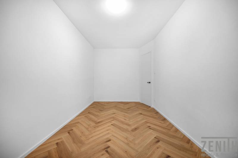 Ein leerer Raum mit weißen Wänden und Holzboden in einer 3-Zimmer-Wohnung.