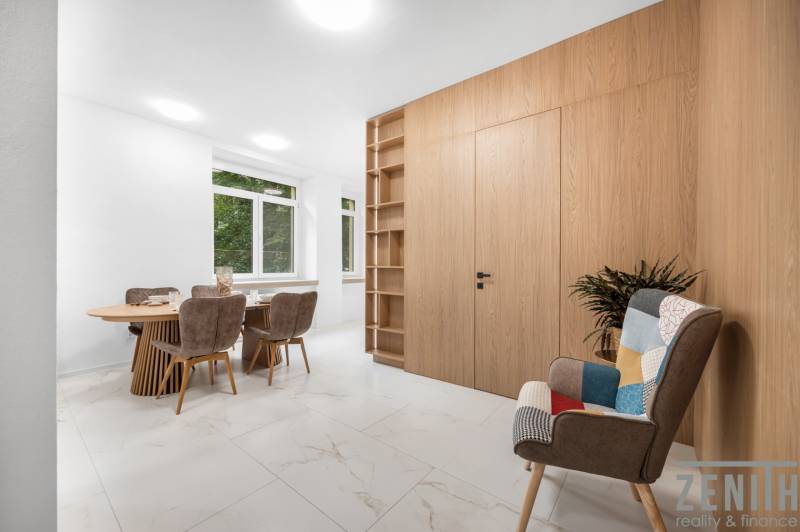 Esszimmer in einer 3-Zimmer-Wohnung mit Holztisch, Stühlen und dekorativem Sessel.