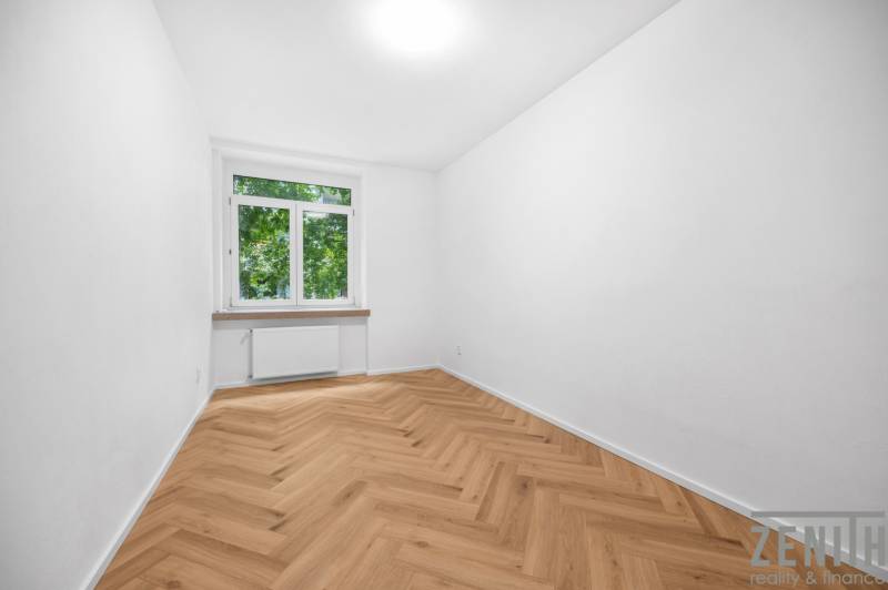 Ein Zimmer in einer 3-Zimmer-Wohnung mit Parkettboden und großem Fenster, helle Dekoration.