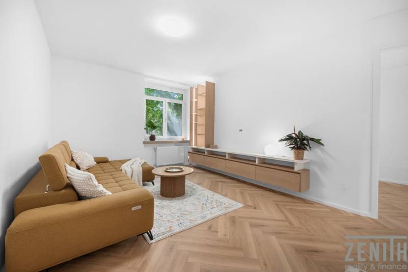 Wohnzimmer in einer 3-Zimmer-Wohnung mit Sofa, Couchtisch und Holzboden.