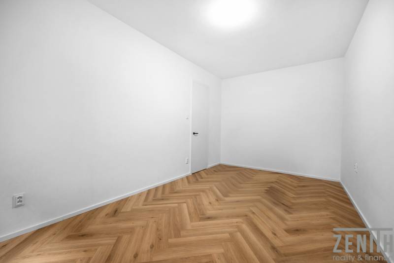 Ein leeres Zimmer in einer 3-Zimmer-Wohnung mit Fischgrätparkettboden.