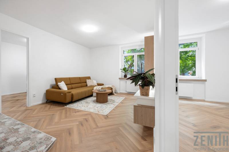 Wohnzimmer in einer 3-Zimmer-Wohnung mit braunem Sofa und Holzboden.