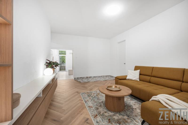 Wohnzimmer in einer 3-Zimmer-Wohnung mit braunem Sofa und Holzmöbeln.