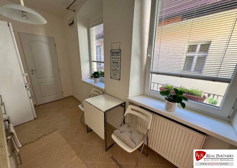 Küche mit Fenstern, Tisch mit Stühlen, Blumen auf der Fensterbank, 2-Zimmer-Wohnung.