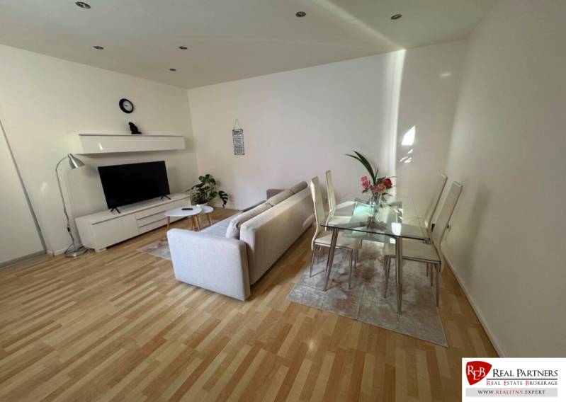 Wohnzimmer mit Sofa, Fernseher und Glastisch in einer 2-Zimmer-Wohnung.
