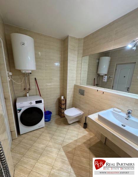 Badezimmer mit Boiler, Waschmaschine, Toilette und Spiegel in einer 2-Zimmer-Wohnung.