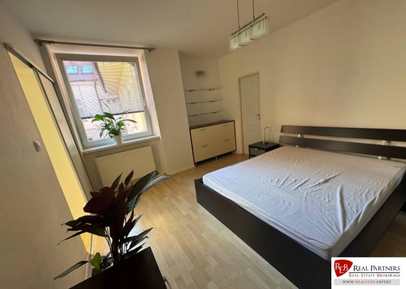 Helles Schlafzimmer mit großem Fenster und Doppelbett in einer 2-Zimmer-Wohnung.