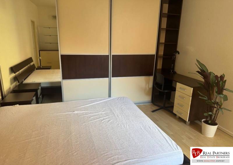 Schlafzimmer in einer 2-Zimmer-Wohnung mit Bett, Schreibtisch und Kleiderschrank.