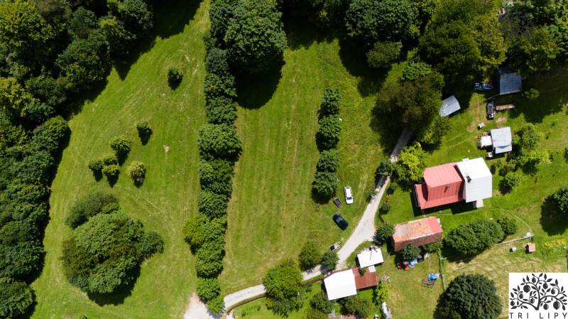 Luftaufnahme von Erholungsgrundstücken in Oščadnica mit Grünflächen, Gebäuden und einer Straße.