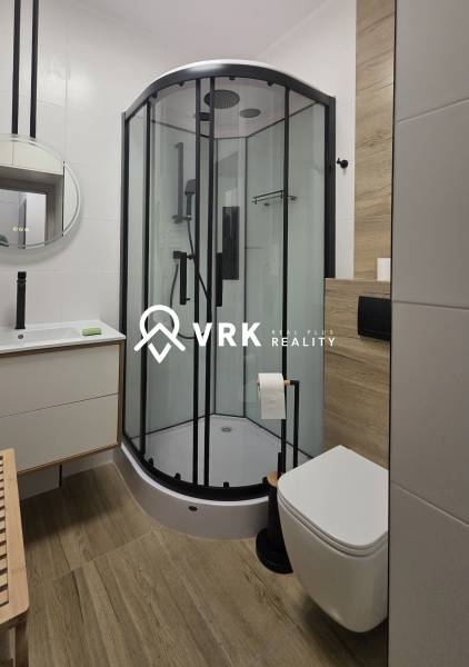 Badezimmer mit moderner Duschkabine und Waschbecken in einer Zweizimmerwohnung.