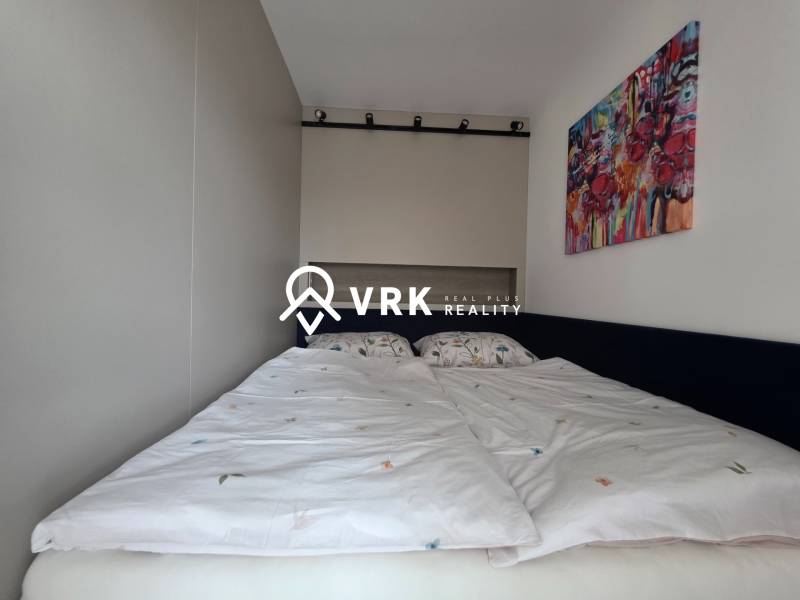 Schlafzimmer in einer 2-Zimmer-Wohnung mit Bett und farbigem Wandgemälde.