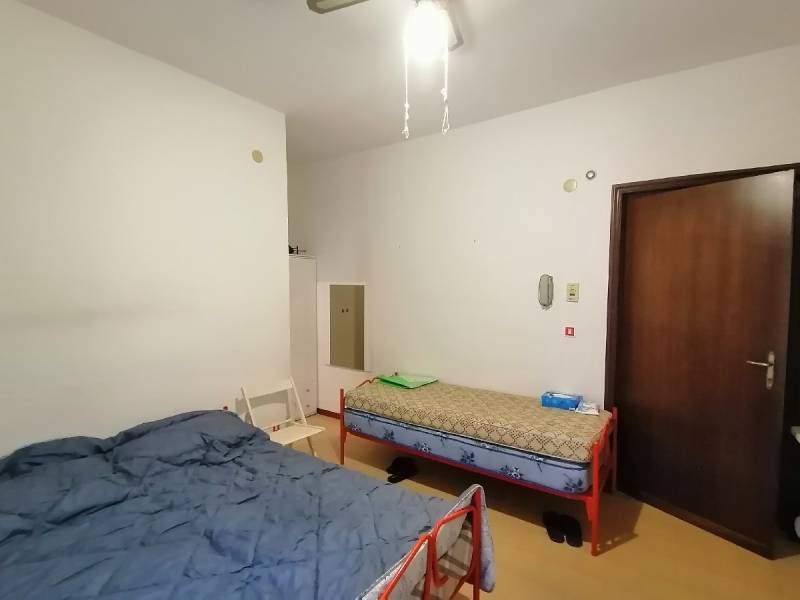 Zwei Betten und ein Stuhl im Zimmer einer Einzimmerwohnung.